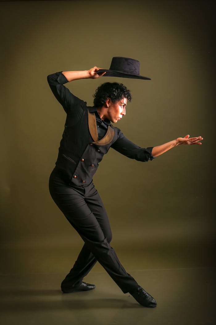 A dynamic flamenco dancer in traditional attire striking a pose with a hat.